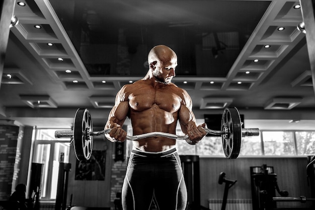 Homme musclé travaillant dans une salle de sport, faire des exercices avec des haltères