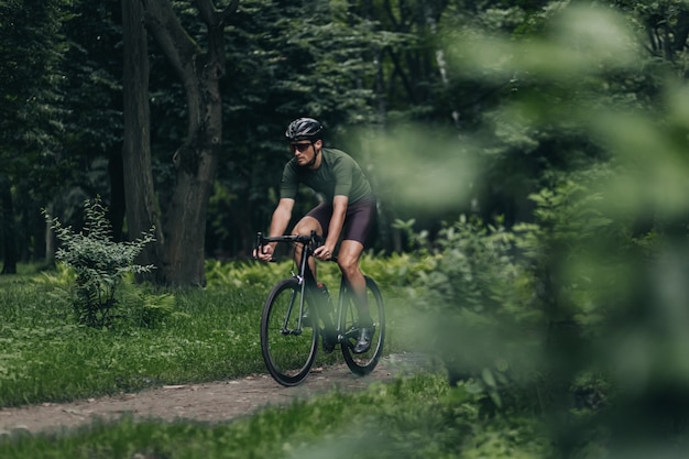 Homme musclé utilisant un vélo noir pour un entraînement actif au parc