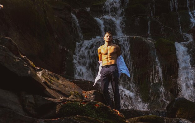 L'homme musclé va nager dans l'eau cascade business concept business businessman se déshabiller à wate