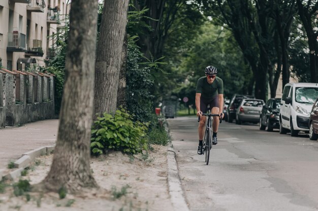 Homme musclé en vêtements de sport à vélo le long de la rue de la ville