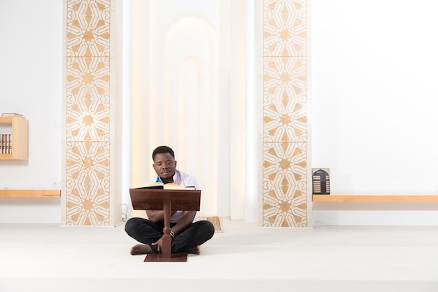 Homme musulman africain lisant le Coran du livre islamique sacré