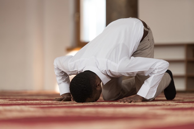 L'homme musulman africain noir prie dans la mosquée