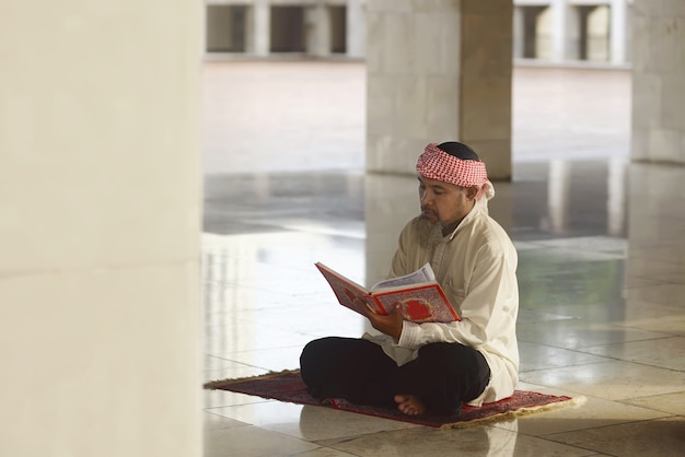 Homme musulman asiatique âgé lisant le Coran