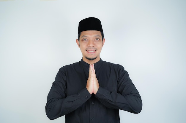 Photo un homme musulman asiatique heureux et souriant se tient debout avec un geste de salut de l'aïd et accueille le ramadan