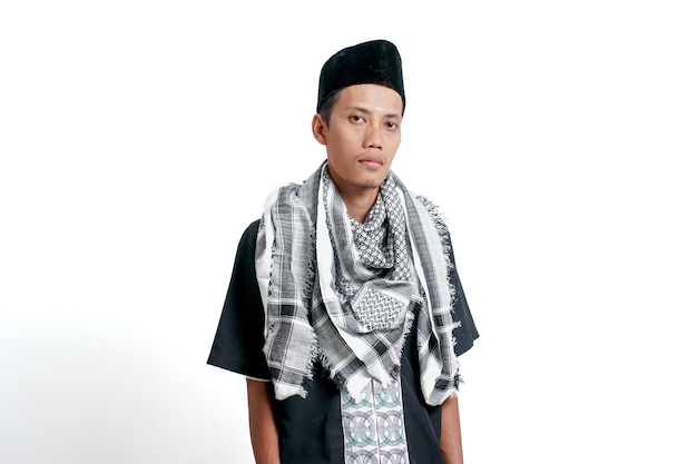 Homme musulman asiatique portant une robe musulmane turban et une casquette debout tout droit isolé sur fond blanc