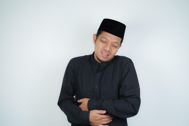 Photo un homme musulman asiatique qui a mal à l'estomac se penche et se tient la main crampes à l' estomac douleurs gastriques