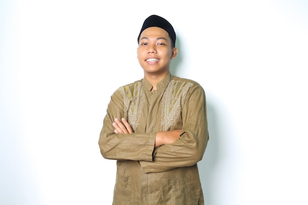homme musulman asiatique souriant debout sur fond blanc isolé avec les bras croisés et la confiance souriante portant des vêtements koko robe islamique