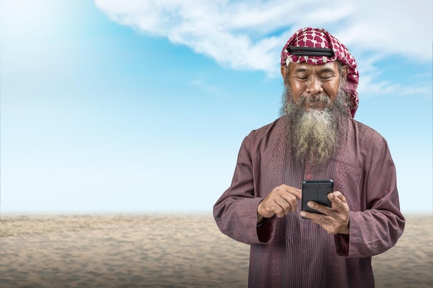 Homme musulman avec une barbe portant un keffieh avec agal à l'aide d'un téléphone portable