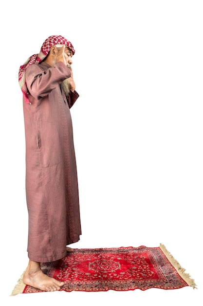 Homme musulman avec une barbe portant un keffieh avec agal en position de prière salat sur le tapis de prière