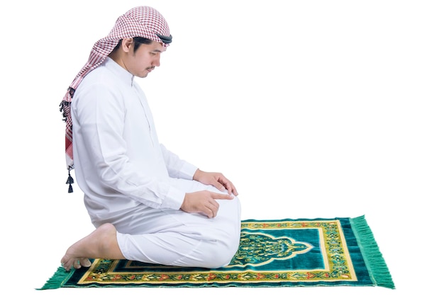 Homme musulman avec keffieh avec agal en position de prière salat sur le tapis de prière