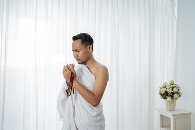 Homme musulman priant en vêtements traditionnels blancs