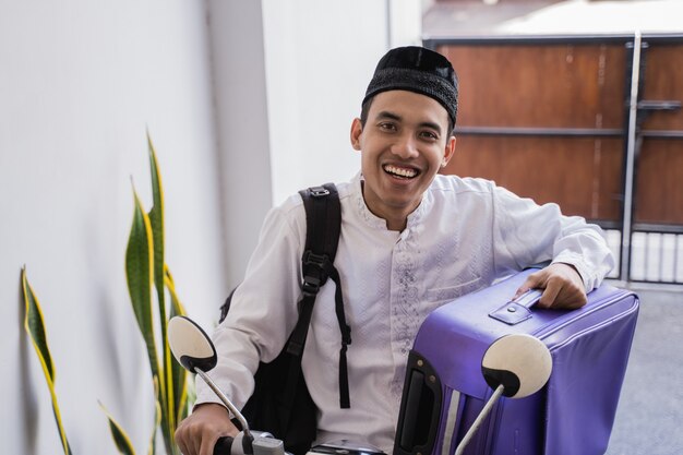 Homme musulman ride moto pour idul fitri balik kampung mudik transportant une valise