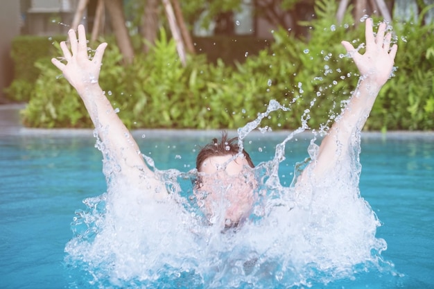 L'homme nage et joue dans la piscine avec un spray