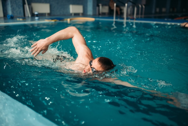 Homme nageur à lunettes nage sur l'entraînement dans la piscine. Formation Aqua Sport, mode de vie sain