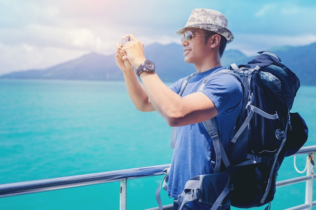 Homme de navire de croisière avec sac à dos à l'aide de téléphone portable en vacances de voyage à l'océan.