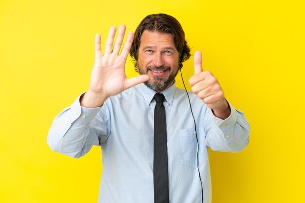 Photo homme néerlandais de télévendeur travaillant avec un casque isolé sur fond jaune comptant six avec les doigts