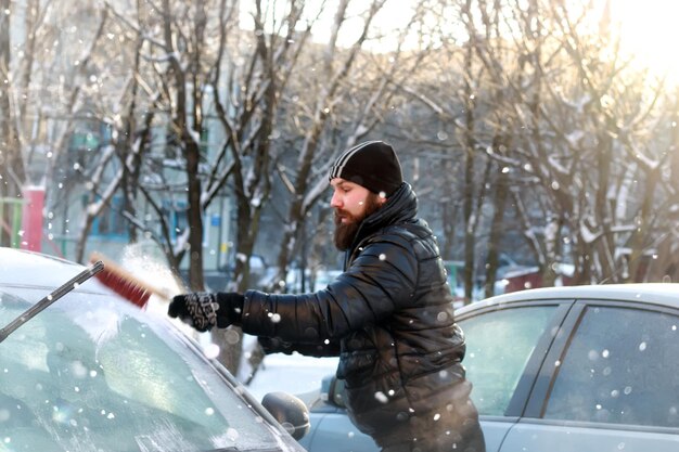 L'homme nettoie la neige du verre à la voiture