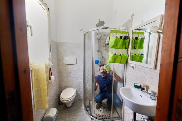 Photo un homme nettoie la salle de bain à la maison.