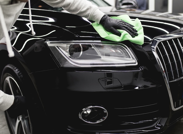 Un homme nettoie une voiture avec un chiffon en microfibre, un concept de détail (ou de voiturier) de la voiture. Mise au point sélective.