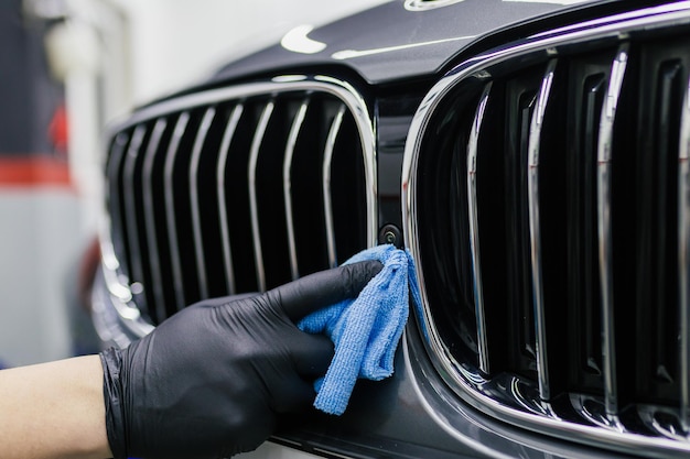 Un homme nettoie une voiture avec un chiffon en microfibre, un concept de voiture (ou de voiturier). Mise au point sélective.