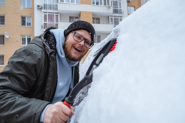 Un homme nettoie la voiture de la neige