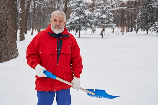 Homme, nettoyage de la neige avec pelle dans le parc.