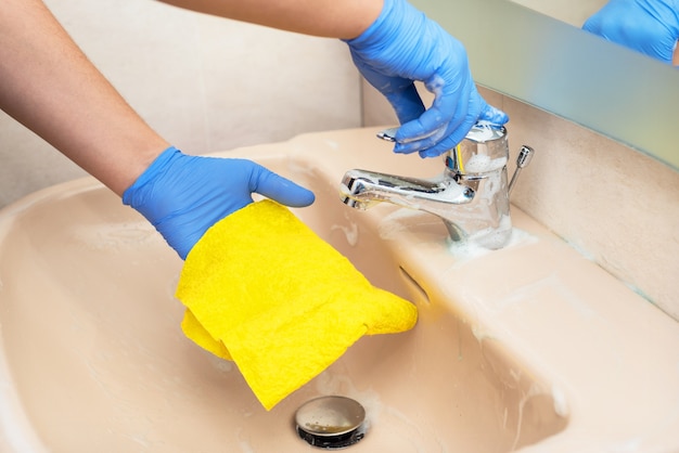 Homme nettoyant le lavabo de la salle de bain