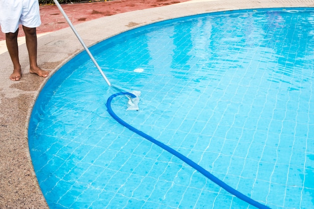 Homme nettoyant une piscine en été. Nettoyeur de la piscine