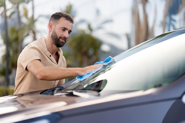 Homme nettoyant sa voiture à l'aide d'un chiffon en microfibre. Concept de service de lavage de voiture