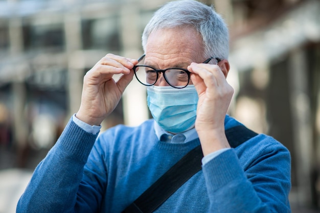 Homme nettoyant ses lunettes embuées à cause du concept de vision du masque covid coronavirus