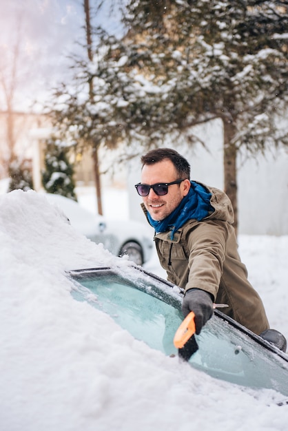 Homme nettoyant une voiture couverte de neige