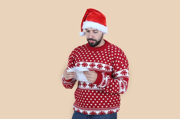 homme, à, noël santa hat, écrit, a, lettre, sourire, fond beige