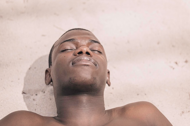 Homme noir allongé sur le sable