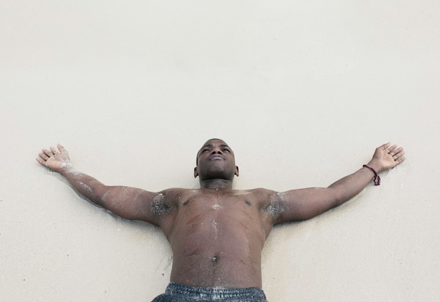 Homme noir allongé sur le sable