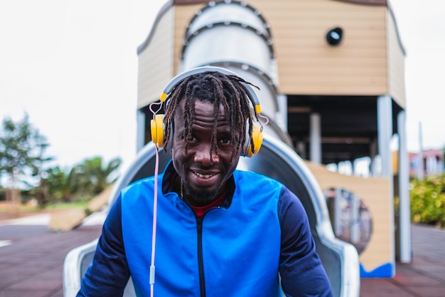 homme noir assis en tenue de sport, écoutant de la musique avec des écouteurs