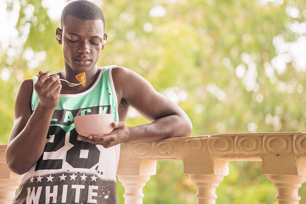 Homme noir ayant des fruits pour le petit déjeuner sur la terrasse