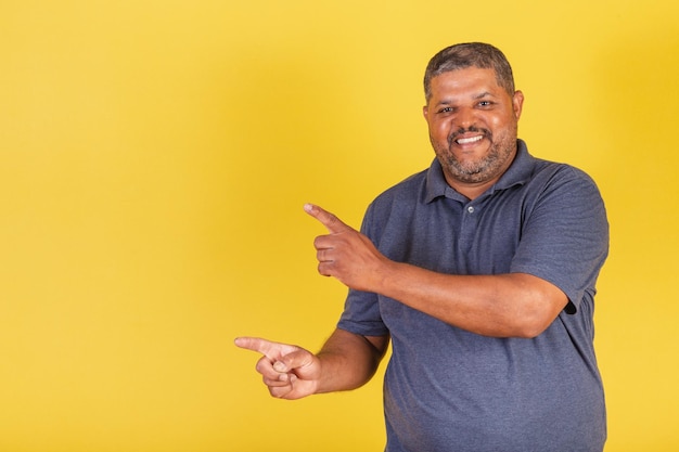 Homme noir brésilien adulte souriant pointant vers la gauche photo publicitaire