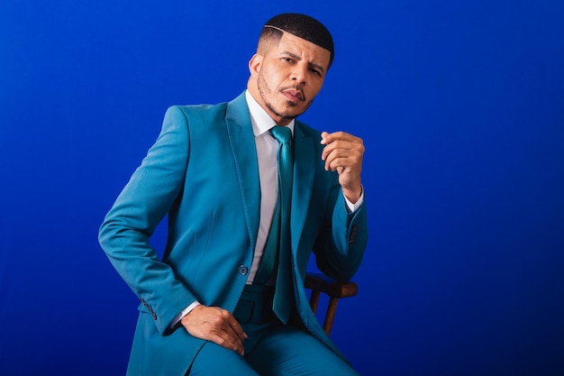 Homme noir brésilien vêtu d'un costume et d'une cravate bleue homme d'affaires chaise en bois pose