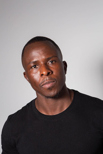 Un homme noir avec un corps de gymnase sculpté portant un t-shirt noir et un pantalon à carreaux de tartan posant dans un studio