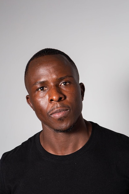 Un homme noir avec un corps de gymnase sculpté portant un t-shirt noir et un pantalon à carreaux de tartan posant dans un studio