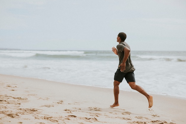 Homme noir courant sur la plage