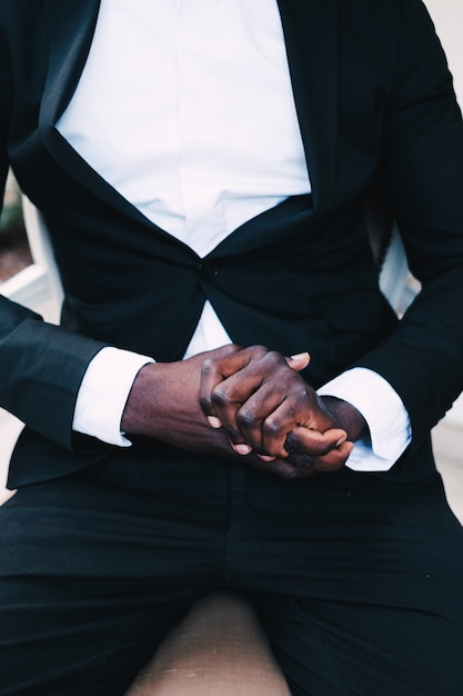 Photo homme noir dans un costume d'affaires assis sur une chaise, concept de mariage.