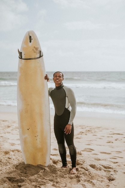 Homme noir debout près de la planche de surf