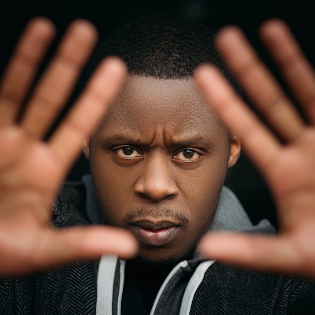 Photo homme noir avec geste d'arrêt en mise au point sélective. homme afro-américain en colère sur fond sombre, expression faciale, photo émotionnelle, concept de protection