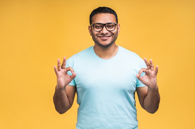 Homme noir indien afro-américain sur isolé sur fond jaune souriant positif faisant signe ok avec la main et les doigts. Expression réussie.