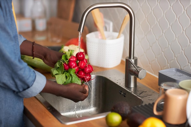 Homme noir lavant des radis et des légumes frais