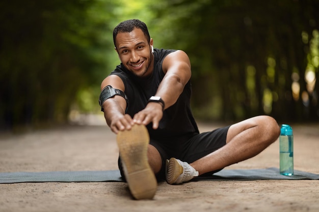 Homme noir musclé positif qui s'étend dans le parc