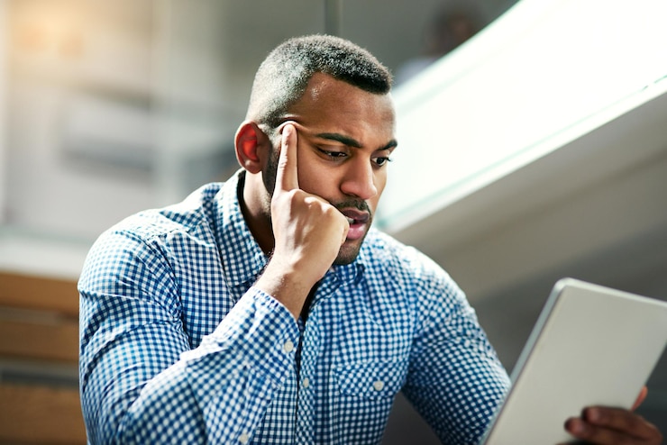 Photo homme noir pensant et tablette au bureau pour lire des informations ou des recherches pour une entreprise en démarrage homme d'affaires idée ou technologie pour des commentaires avec la planification résolution de problèmes ou brainstorming sur le lieu de travail
