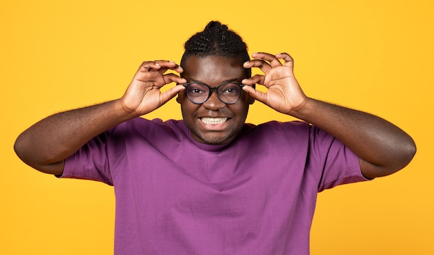 Homme noir regardant la caméra à travers des lunettes sur fond jaune