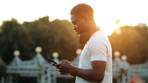 L'homme noir regarde l'écran du smartphone à l'arrière du soleil